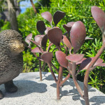 一株株銅葉舒展枝姿，在陽光下閃耀生命的光澤，鳥兒靜靜守望，為街道增添自然的詩意。
