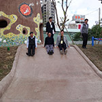 新業(yè)建設(shè)卓勝隆董事長(中)與來賓童心大發(fā)，一起玩溜滑梯。