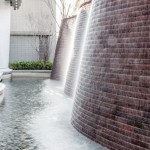 與接待大廳相對，僅隔一道玻璃落地窗即為「戶外水瀑牆」。流水潺潺與磚石沖刷出平整的紋路，水光相映下霧氣生騰，彷若仙境。－【新業(yè)觀峰】。