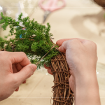 先以鐵絲穿過(guò)藤圈並收好，抓一把雪松，繞過(guò)後拉緊，再取一把雪松，在第一把根部接上，以此將雪松綁完。