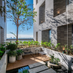 四季合院，每三層設(shè)計(jì)一處公共大露臺(tái)，從梯廳走入彷彿大家庭的合院(埕)，提供住戶們休憩及交誼空間，搭配四季主題的呼應(yīng)，此為七樓的夏季-種植小花紫薇與厚葉石斑木。