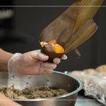 將粽葉三分之一處折起，交叉形成漏斗狀，轉(zhuǎn)著處末端折一個(gè)折角，再將內(nèi)餡包入。